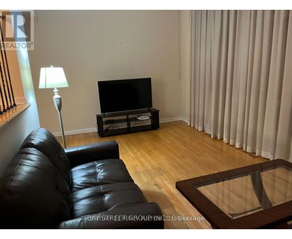 A black leather sofa sits in front of a television in a living room.