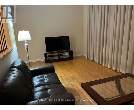 A black leather sofa sits in front of a television in a living room.