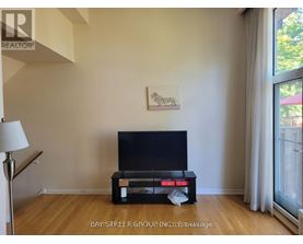 A black television sits on a wooden stand in a room with a painting on the wall.