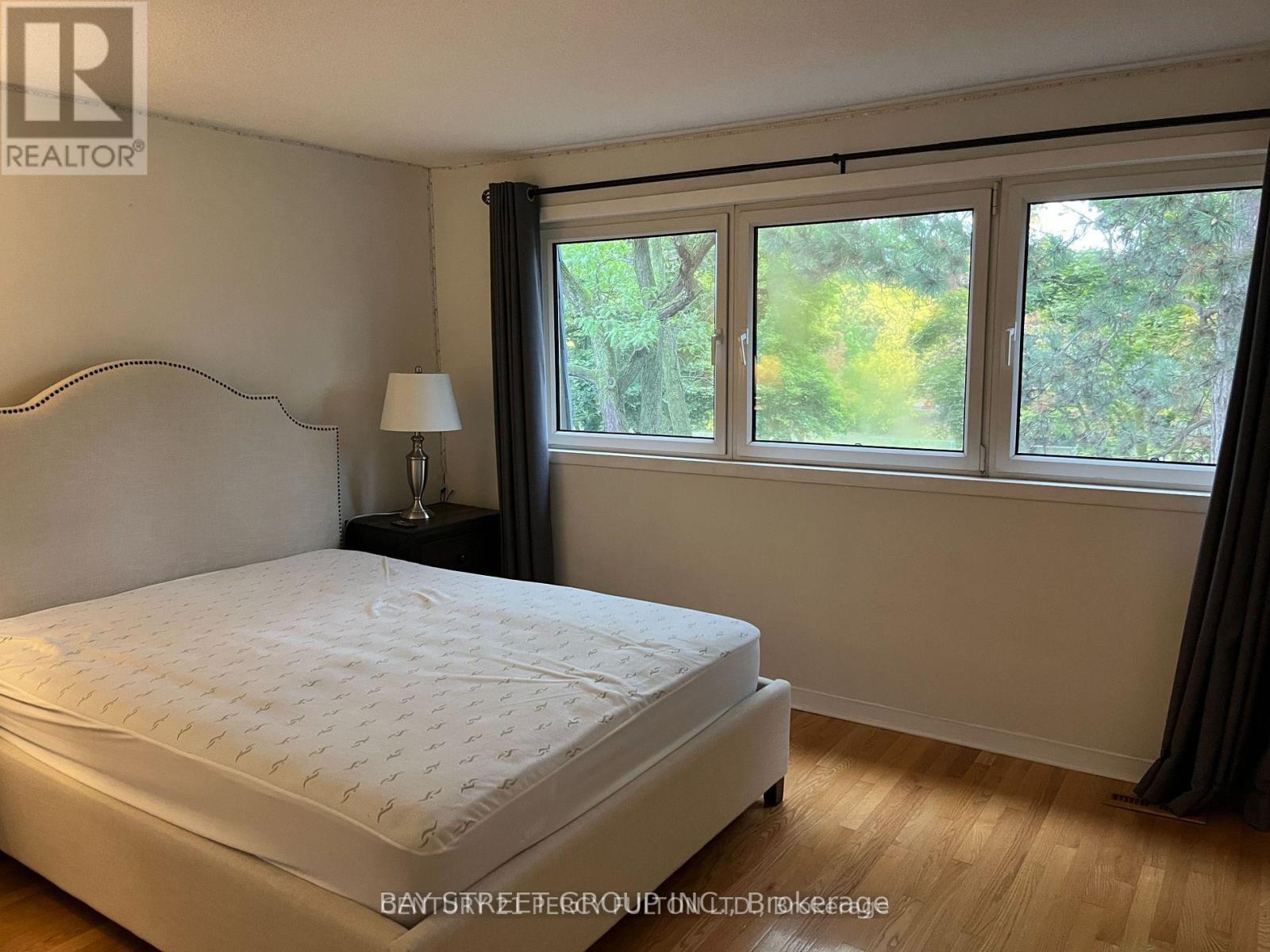 A bedroom with a large bed and a window with a view of trees.