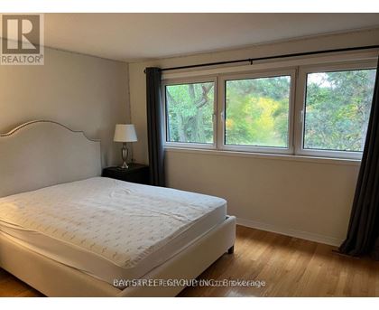 A bedroom with a large bed and a window with a view of trees.