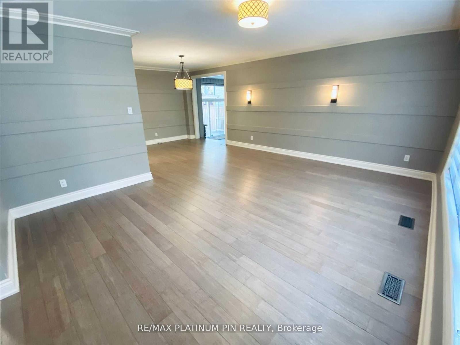 A spacious room with wood flooring and a ceiling light.