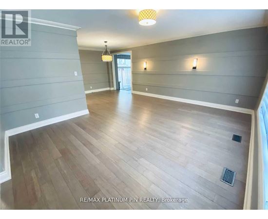 A spacious room with wood flooring and a ceiling light.