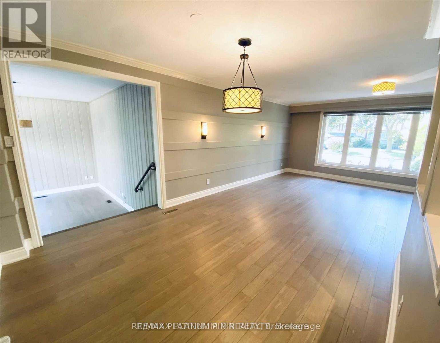 A well-lit room with wooden flooring and a chandelier hanging from the ceiling.