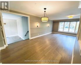 A well-lit room with wooden flooring and a chandelier hanging from the ceiling.