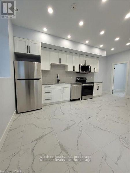 A modern kitchen with a marble floor and stainless steel appliances.