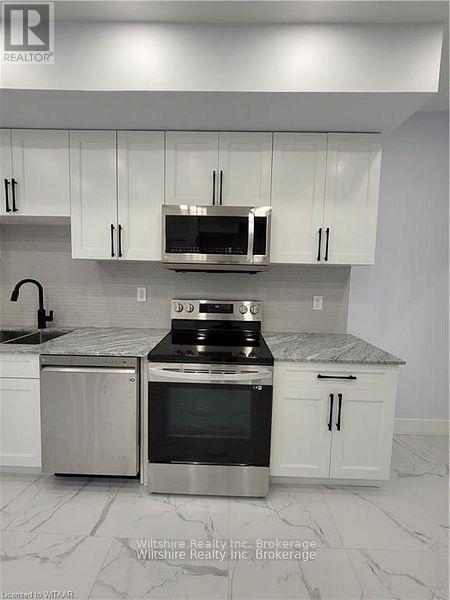 A kitchen with white cabinets and a marble countertop.