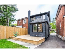 A modern house with a black exterior and a wooden deck.