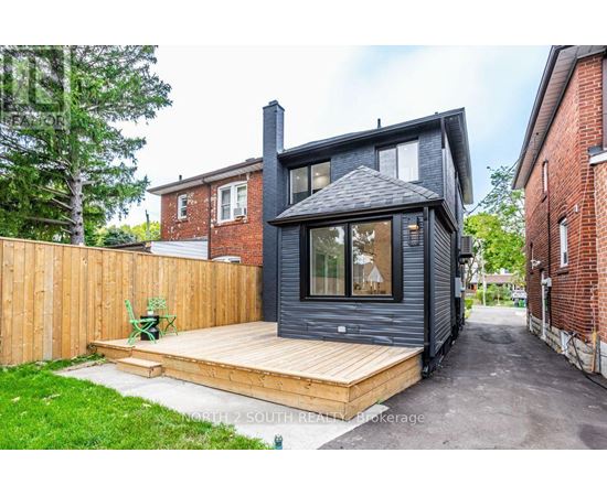 A modern house with a black exterior and a wooden deck.