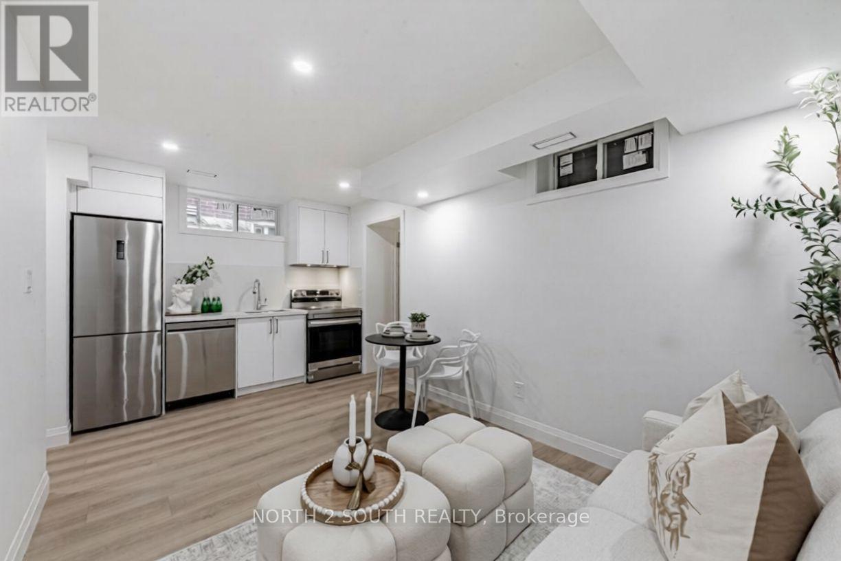 A modern kitchen with stainless steel appliances and a dining area with a round table and chairs.