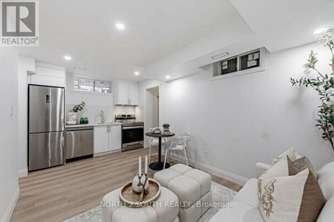 A modern kitchen with stainless steel appliances and a dining area with a round table and chairs.