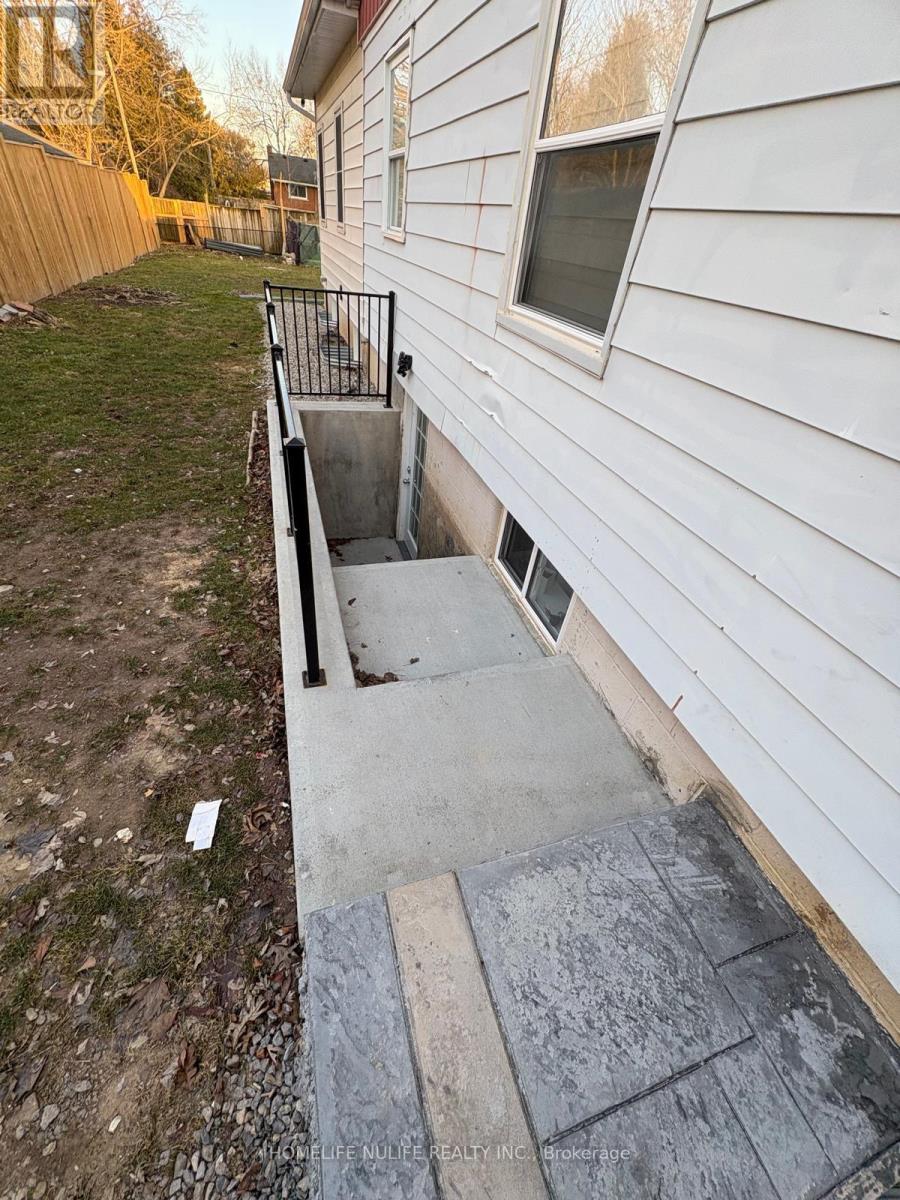 A white house with a concrete staircase leading to a basement entrance.