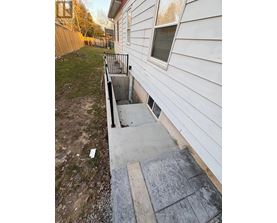 A white house with a concrete staircase leading to a basement entrance.