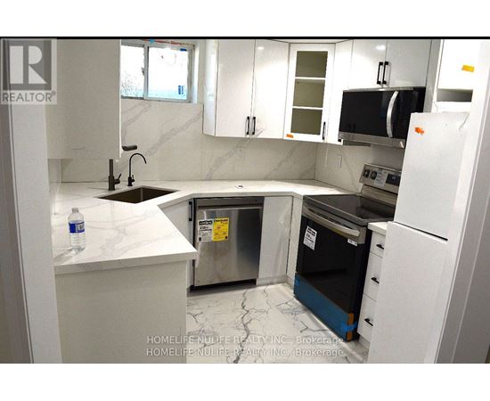 A kitchen with white cabinets and a black fridge.