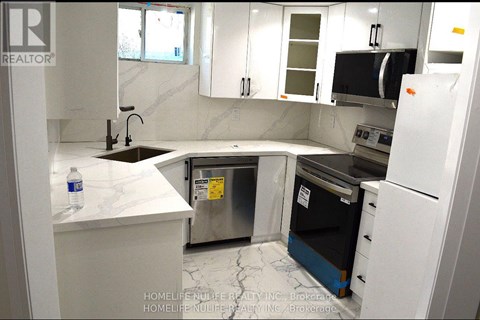 A kitchen with white cabinets and a black fridge.