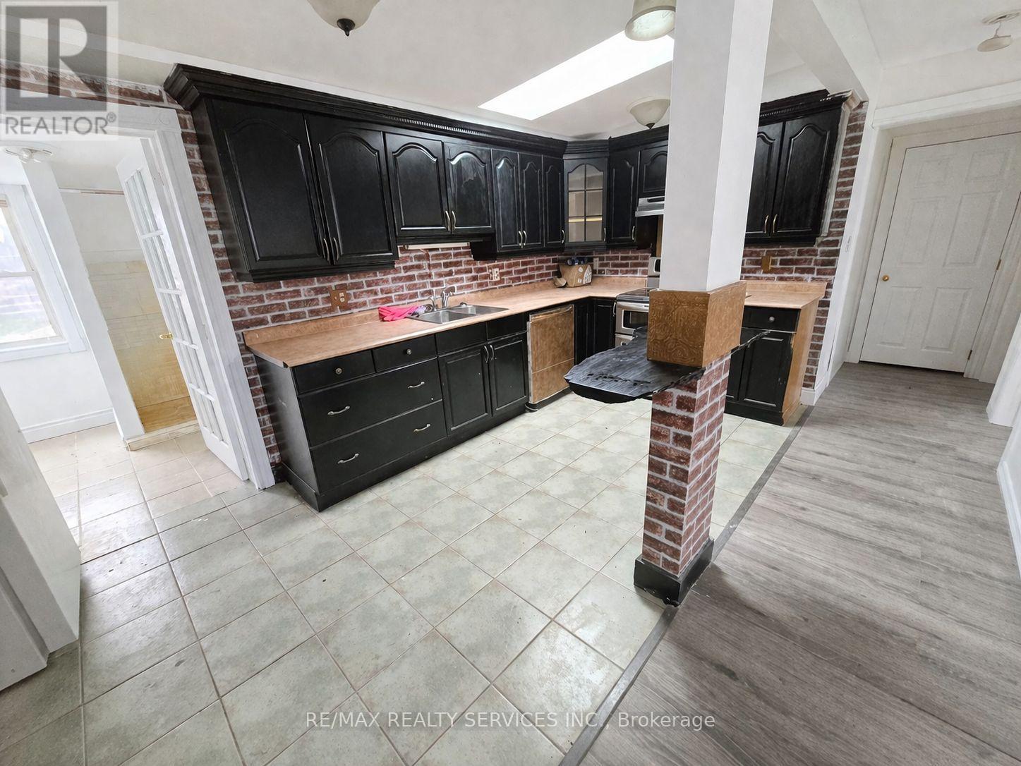 A kitchen with black cabinets and a brick backsplash.