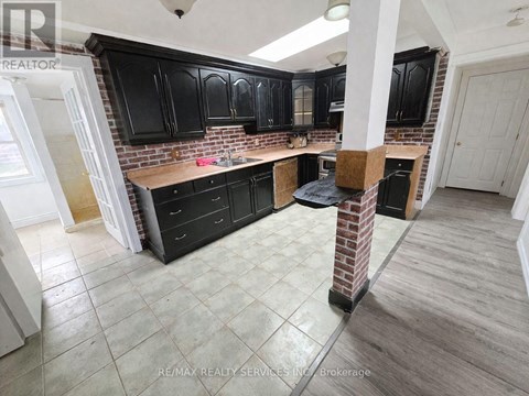 A kitchen with black cabinets and a brick backsplash.