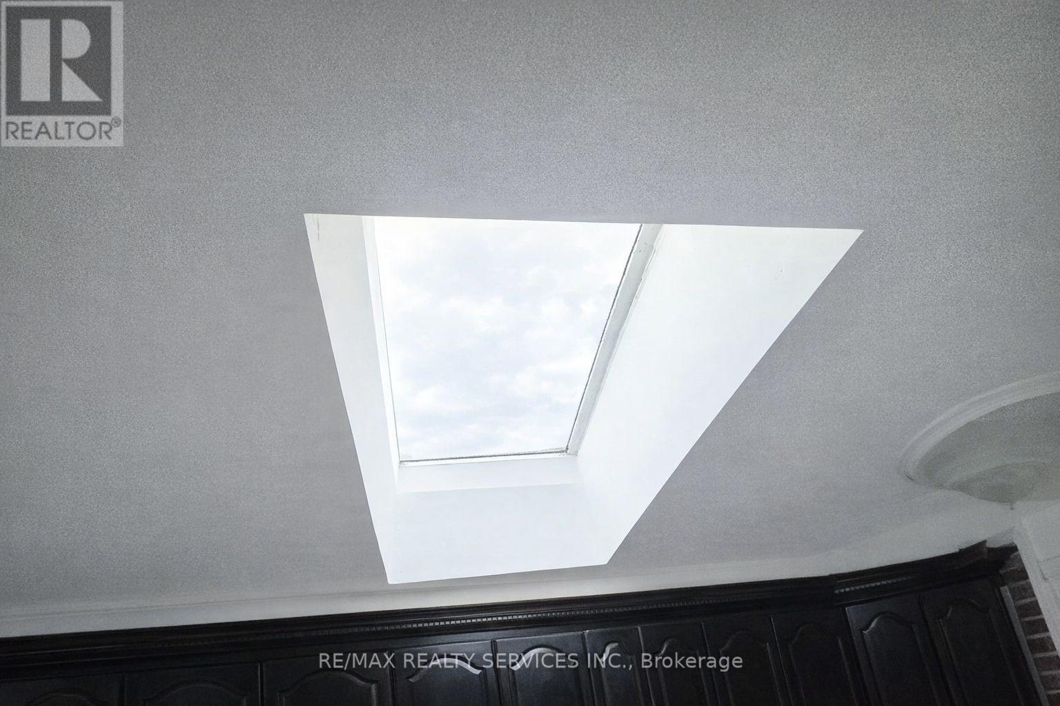 A skylight in a ceiling with a logo of a realtor on the top left.