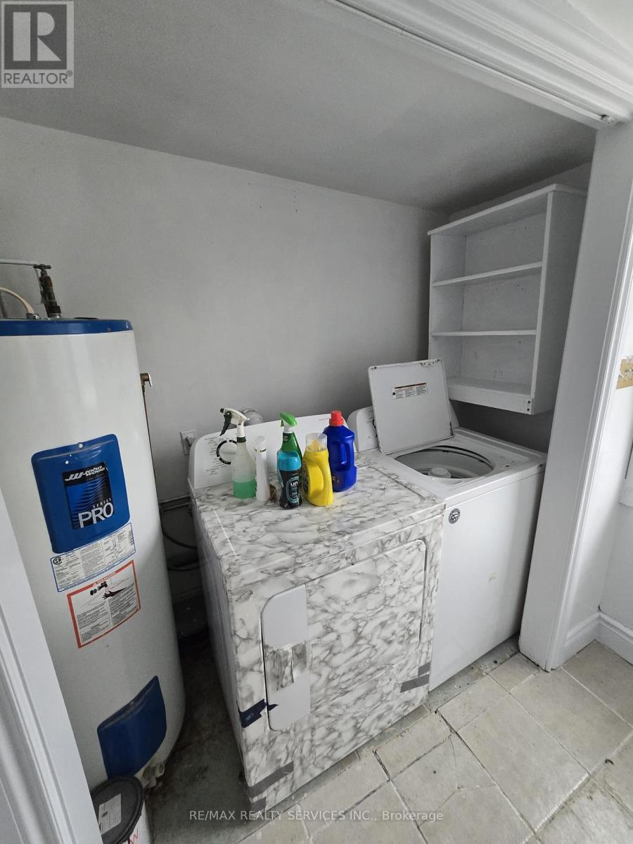 A white washing machine sits next to a white dryer in a small laundry room.