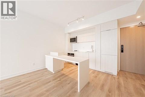 A white kitchen with wooden floors and a white cabinet with a microwave and oven.