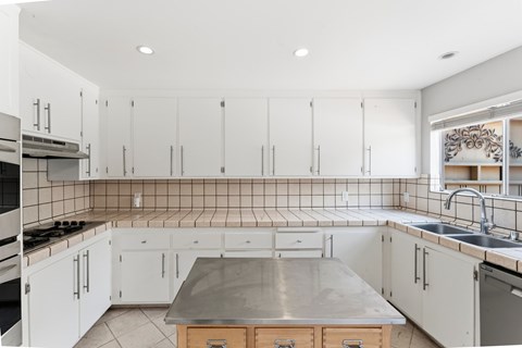 A kitchen with white cabinets and a tile backsplash.