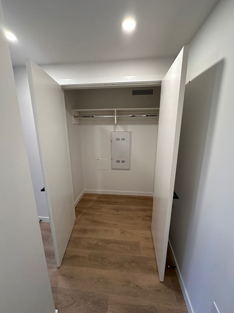 A white hallway with a wood floor and a white door on the right.
