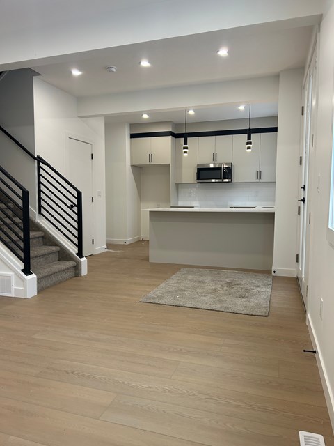 A modern kitchen with a staircase on the left side.
