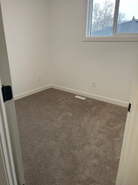 A room with a carpeted floor and a window.