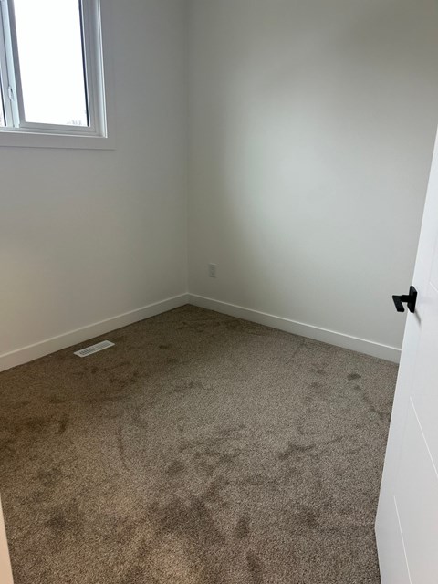 A room with a carpeted floor and a window.