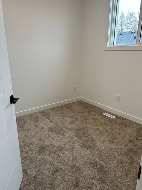 A room with a carpeted floor and a window.