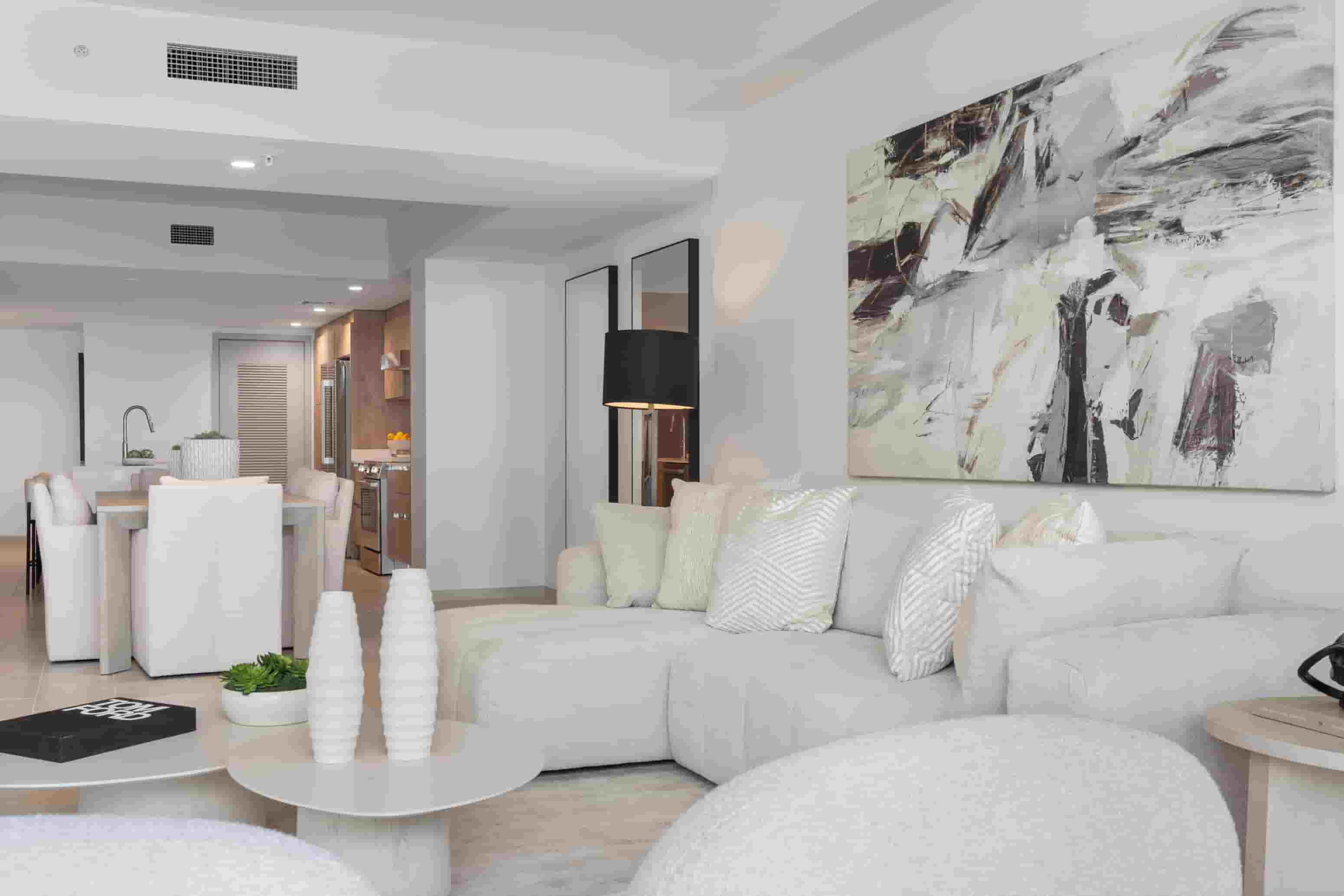 A modern living room with white furniture and a large abstract painting on the wall.