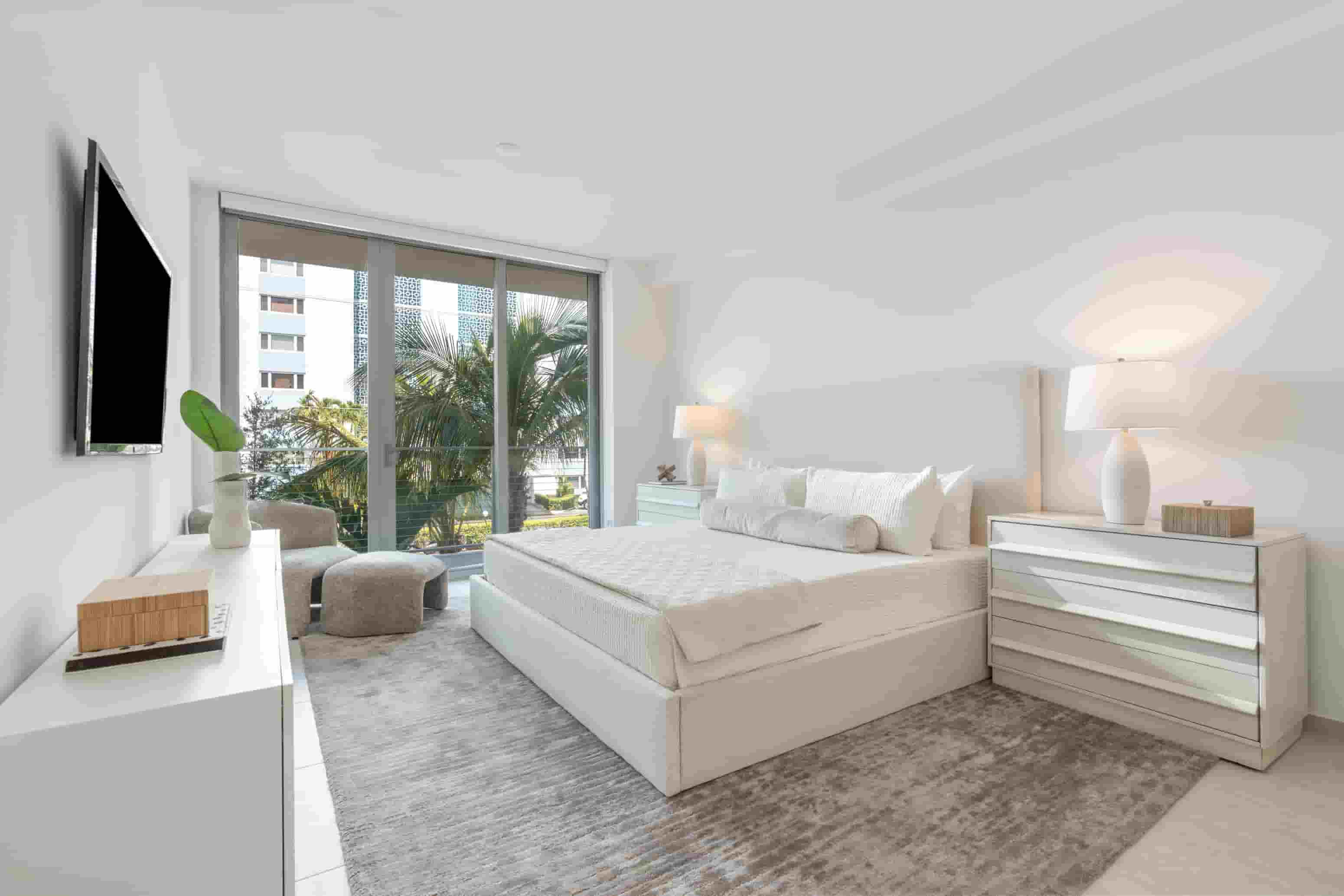 A modern bedroom with a large bed and a flat screen TV mounted on the wall.