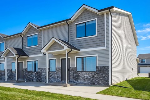 A modern house with grey siding and stone accents.