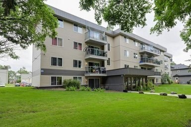 A large apartment complex with multiple balconies and green lawns in front.