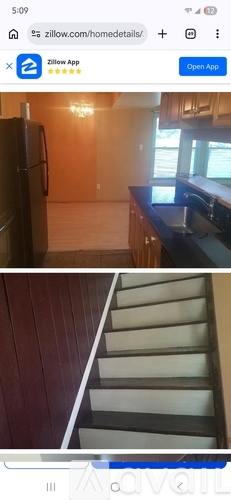 A kitchen with a refrigerator and a staircase.