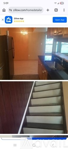 A kitchen with a refrigerator and a staircase.
