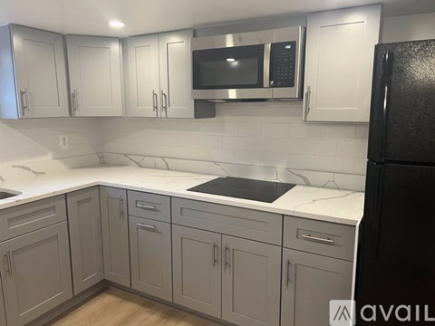 A kitchen with white cabinets and a black refrigerator.