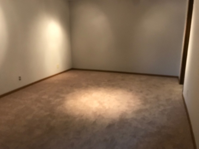 A room with a carpet and a light on the floor.