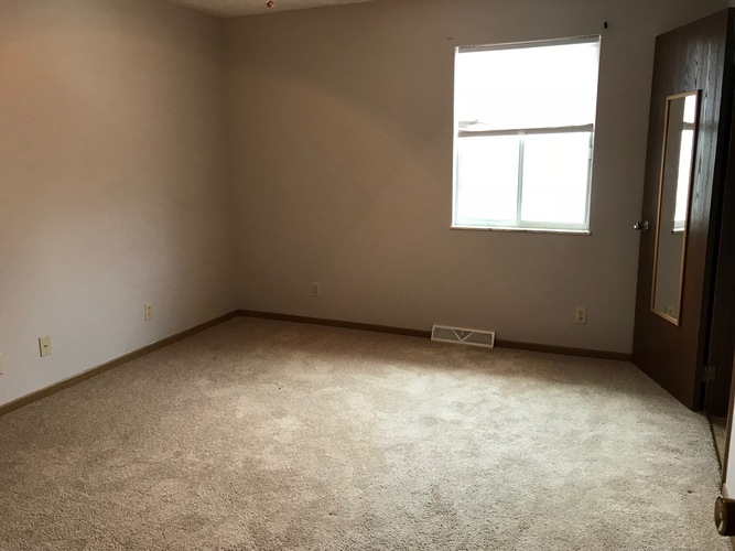A room with a carpeted floor and a window.