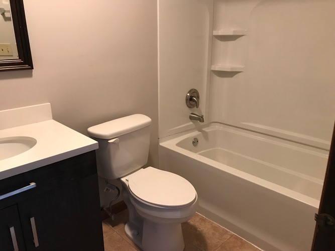 A white toilet sits next to a bathtub in a bathroom.