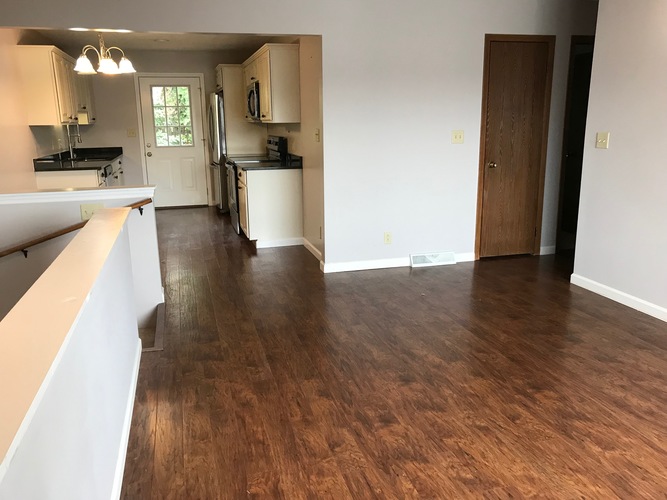 A kitchen with white cabinets and a black fridge.