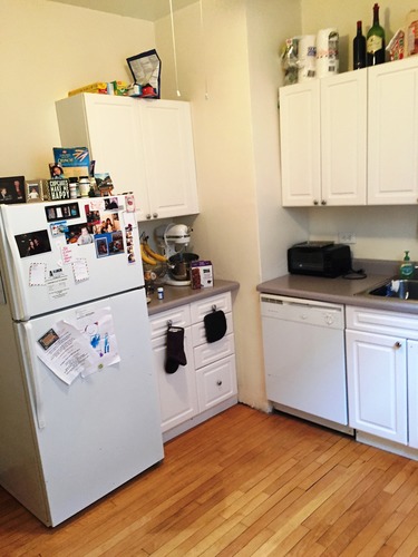 A small kitchen with a white fridge and cabinets.