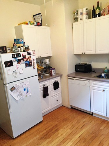 A small kitchen with a white fridge and cabinets.