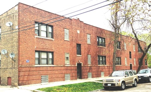 A red brick building with a tree in front of it.