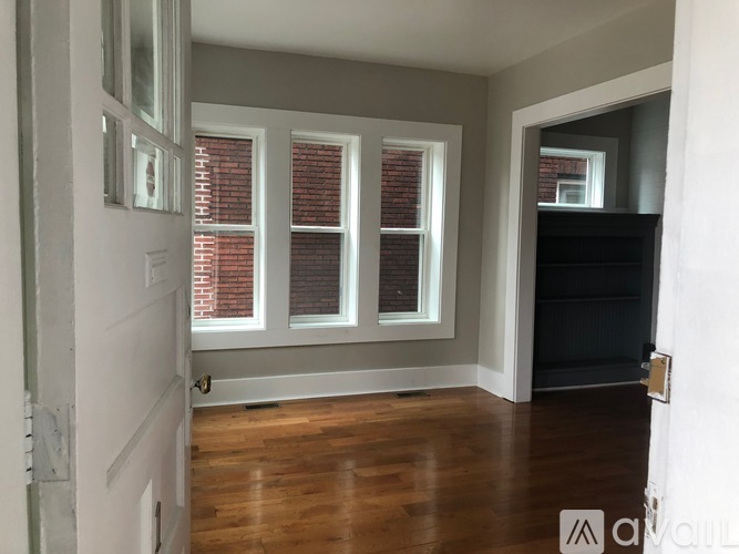 A room with wooden floors and two windows with red blinds.