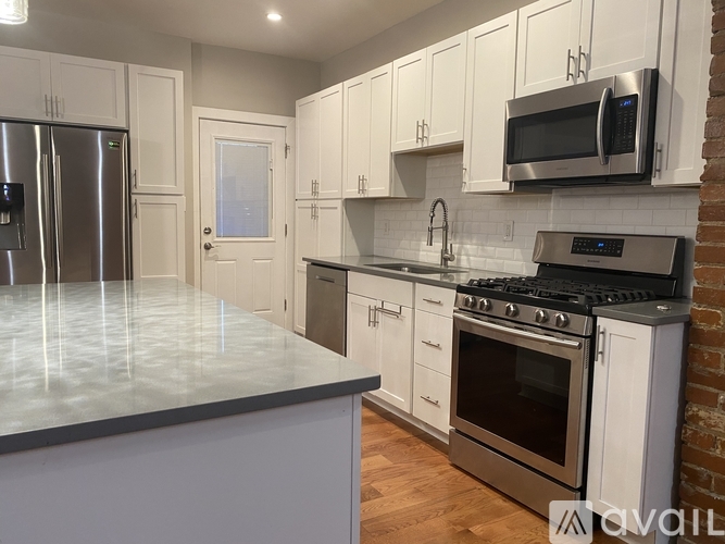 A kitchen with white cabinets and a brick wall.