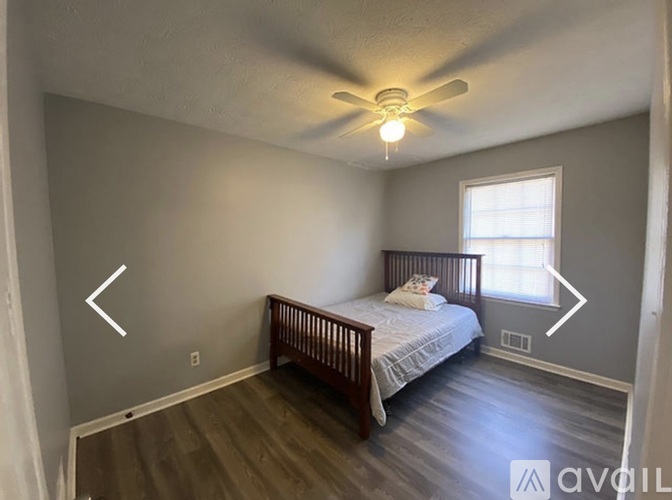 A bedroom with a bed, a window, and a ceiling fan.