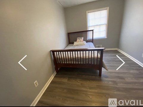 A baby's crib sits in a corner of a room with a window.