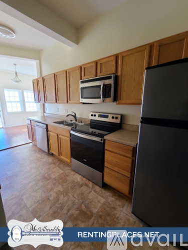A kitchen with wooden cabinets and a black refrigerator.