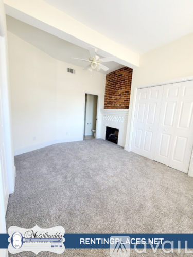 A room with a carpeted floor and a ceiling fan.
